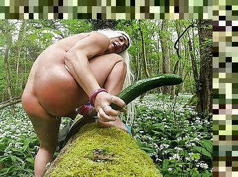 Tygra Blonde sissy eats a whole tasty cucumber in woods.