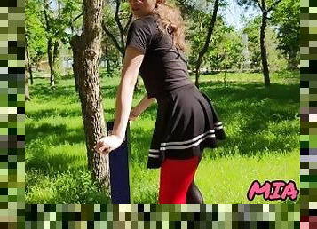 A BEAUTIFUL GIRL IN GLASSES WALKS IN A PARK IN A SHORT SKIRT ATTRACTING THE ATTENTION OF OTHER PEOPL