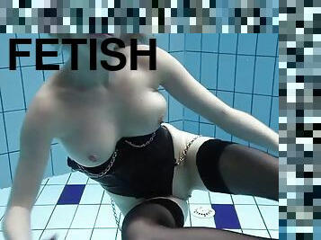 Anetta swims in a pool in her nylon stockings and a corset