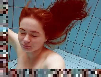 Lola, a girl with big natural tits, swims underwater.