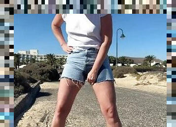 girl pisses in jeans shorts at the street in public