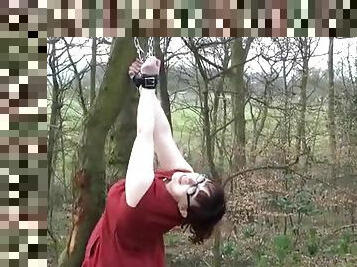 Girl in glasses cuffed to a tree in public park