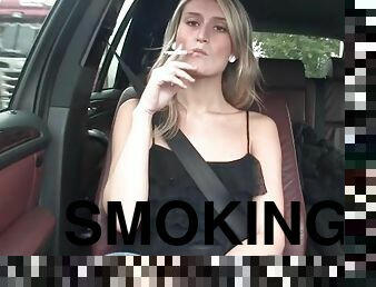 Sexy blonde smokes cigarette in the car