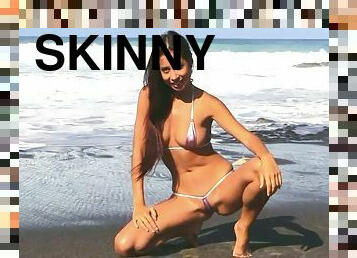 Slim tall brunette babe poses naked on the beach