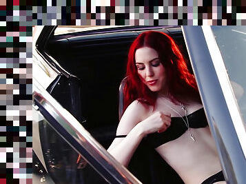 Slender spicy redhead is posing in a hot rod