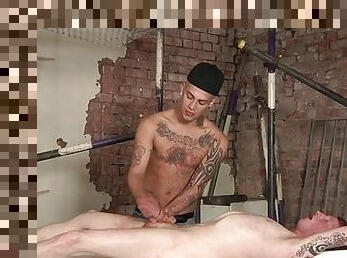 Tattooed guy tied to a table gets a handjob