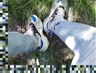 Young guy in sneakers and blue jeans smoke in the forest