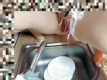 Charlady is pissing on dishes in sink at the kitchen
